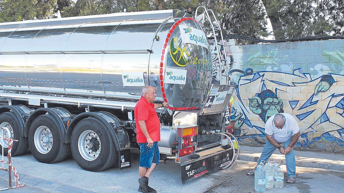 Un vecino llena garrafas de agua de un camión cisterna en Baena.