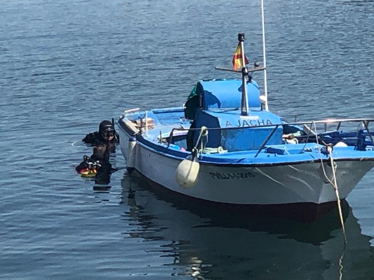 Dos buzos de la policía nacional buscan el arma en la dársena de Ribeira. Están centrados en un punto de la zona de embarcaciones menores , junto a la rampa, a unos 20 metros del muelle