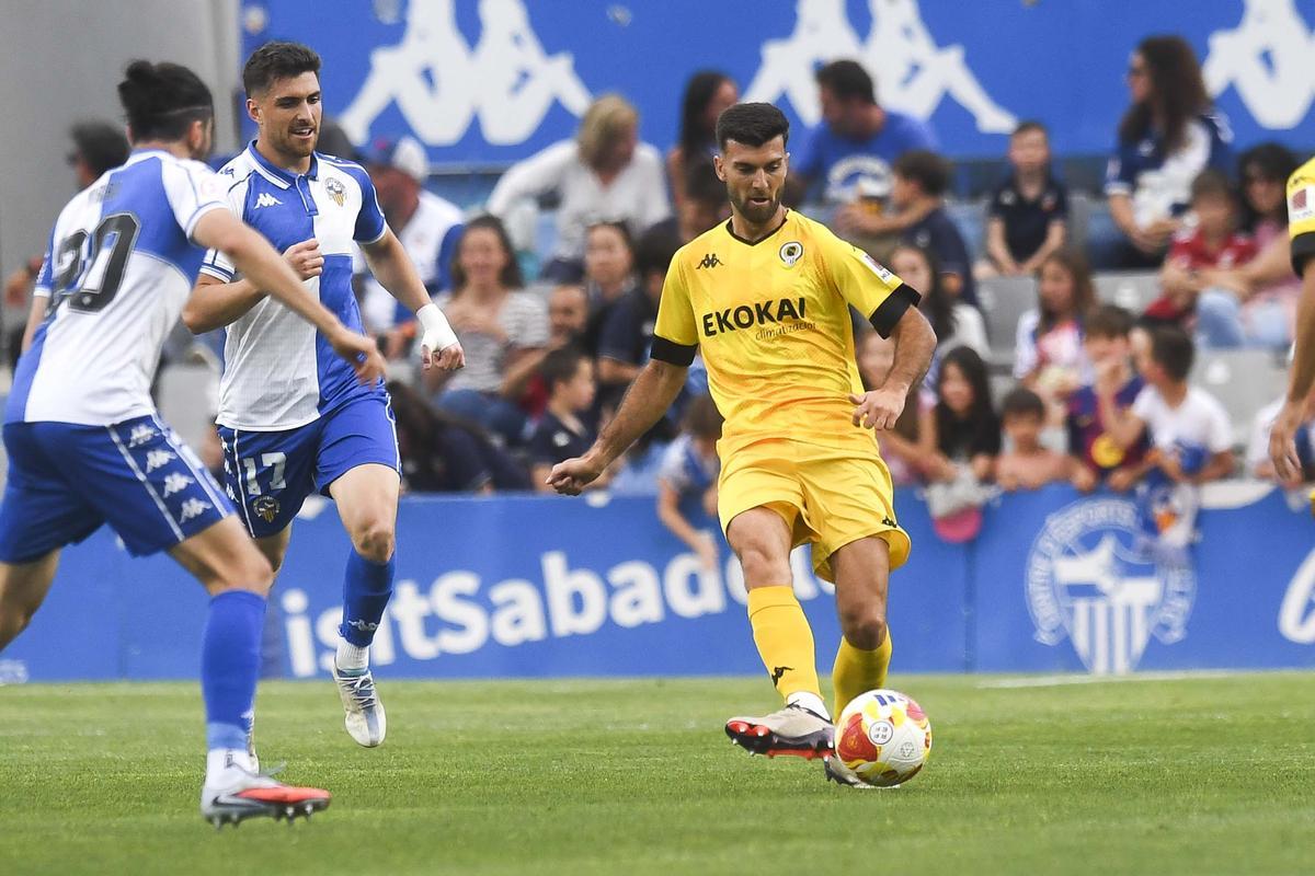 Josep Calavera pasa la pelota perseguido por Agustín Coscia en la Nova Creu Alta de Sabadell.