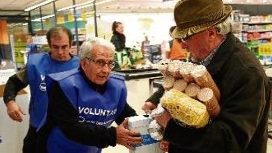 Un comprador donant aliments a voluntaris del Gran Recapte a un supermercat Mercadona de Girona.