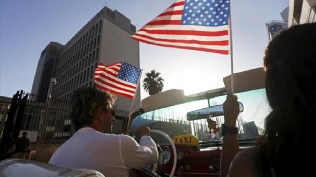 CELEBRACIÓN Un taxista cubano pasa frente a la nueva embajada de EEUU en Cuba, en La Habana.