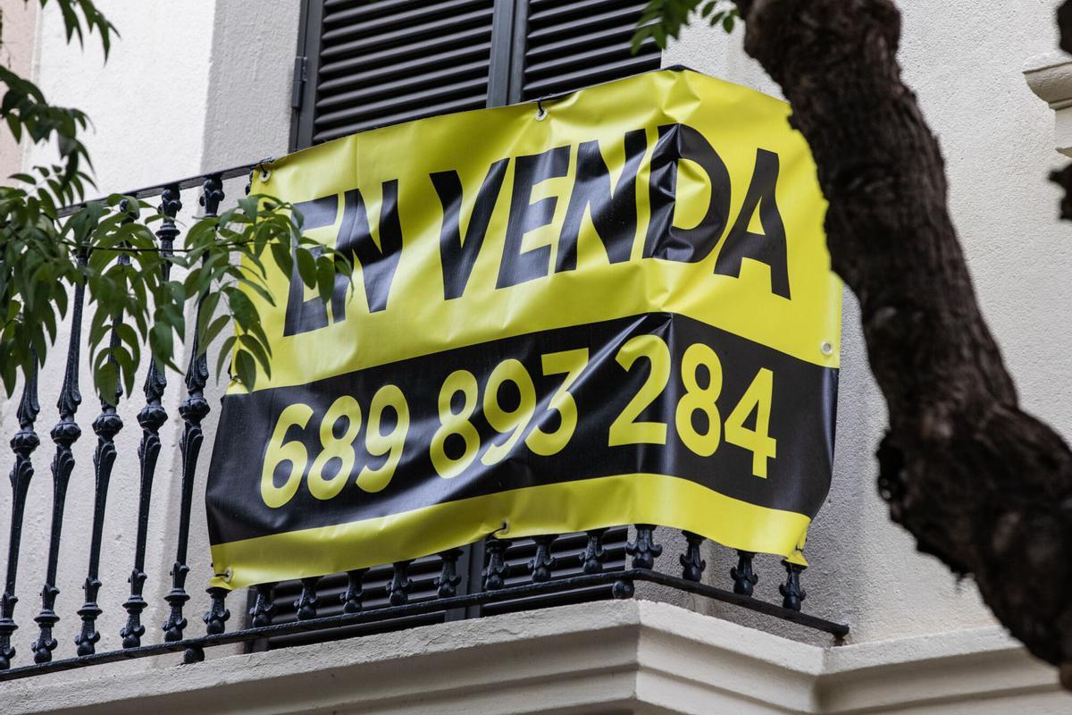 Pancarta de piso en venta encima de un balcón