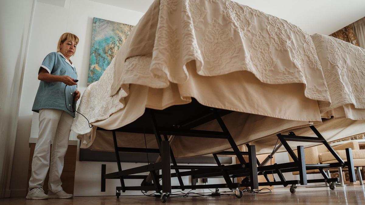 Una camarera de pisos del Hipotels Playa de Palma Palace muestra el funcionamiento de una cama elevable