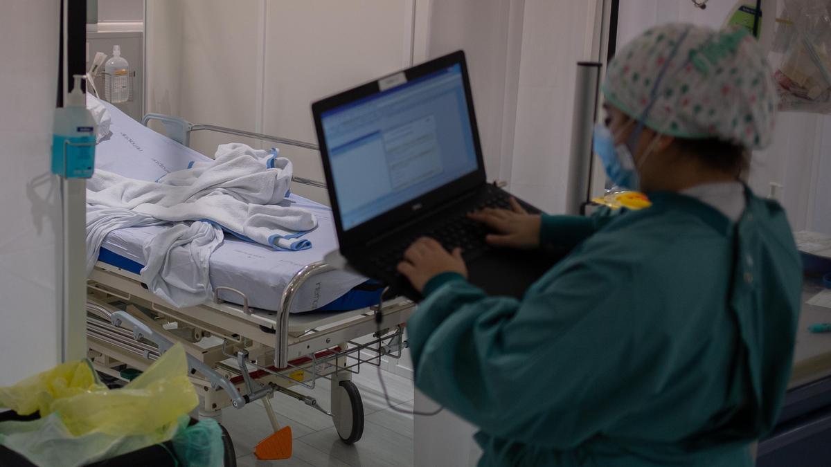 Una sanitaria toma datos en su ordenador en una habitación de una Unidad de Cuidados Intensivos  (UCI), foto de recurso