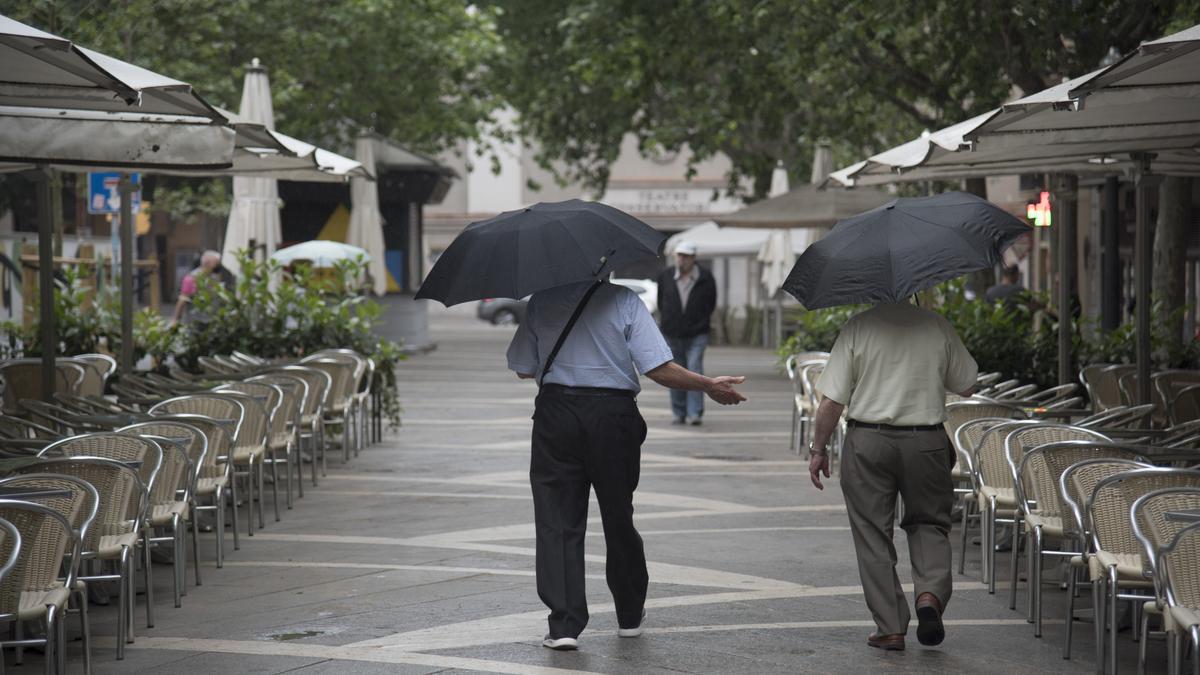Dos homes passegen pel Passeig Pere III de Manresa durant el temporal de pluja d&#039;aquest dimarts