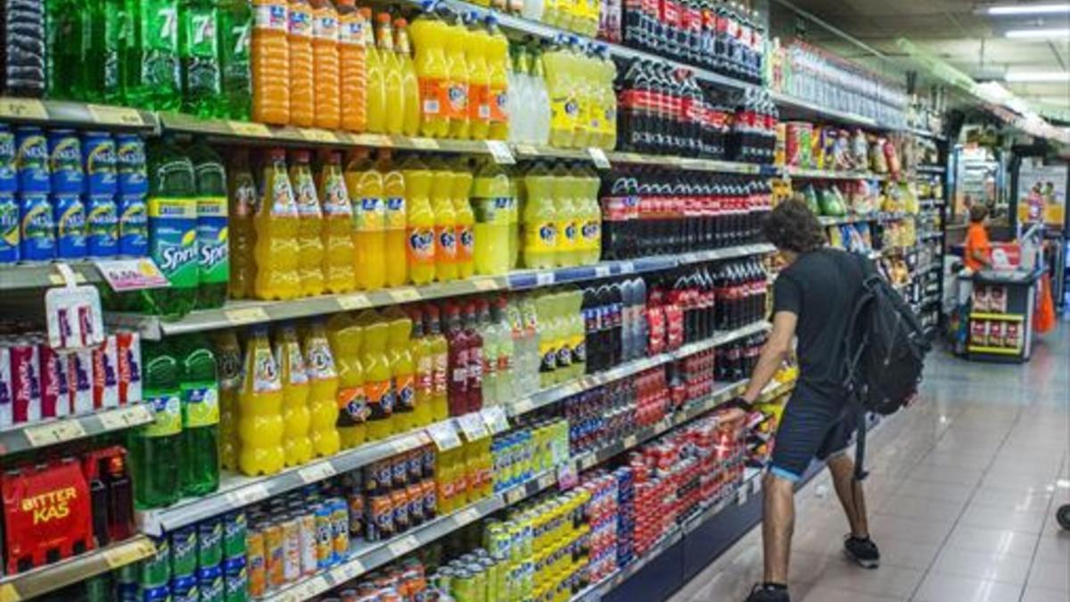 En la diana 8Un joven, ante la estantería de refrescos de cola, en un supermercado de Barcelona.