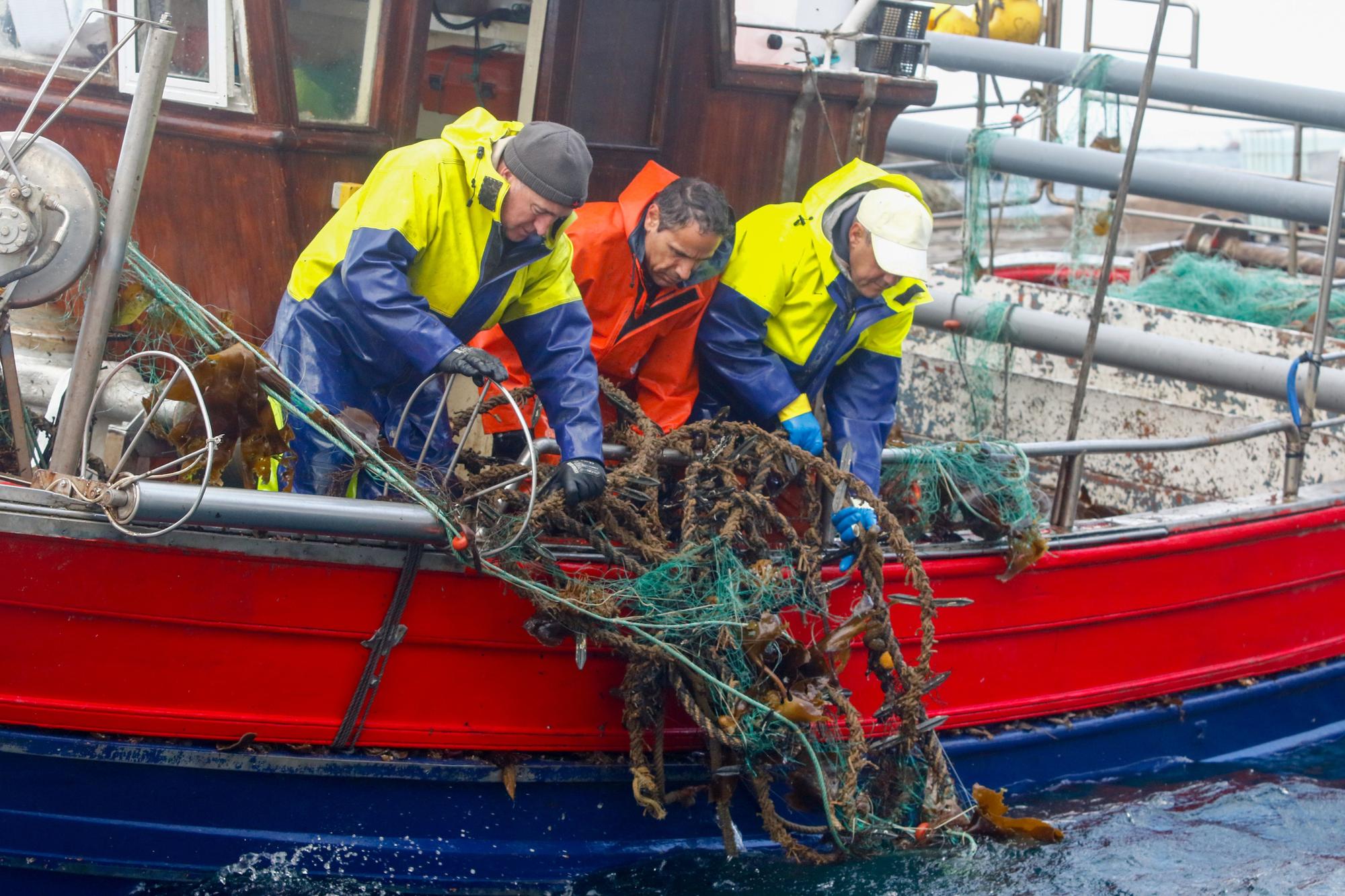 Pescadores retirando cuerdas de sus &quot;miños&quot;.