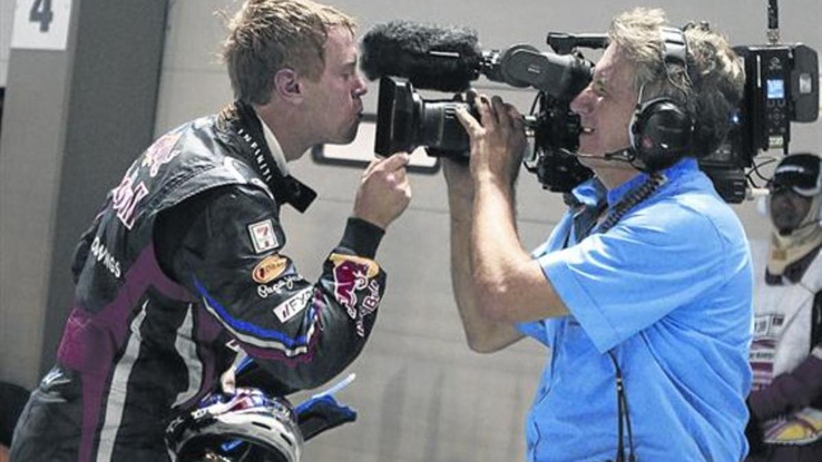 El tetracampeón alemán Sebastian Vettel besa el objetivo de una cámara del Mundial de F-1 tras ganar el GP de Singapur del 2011.