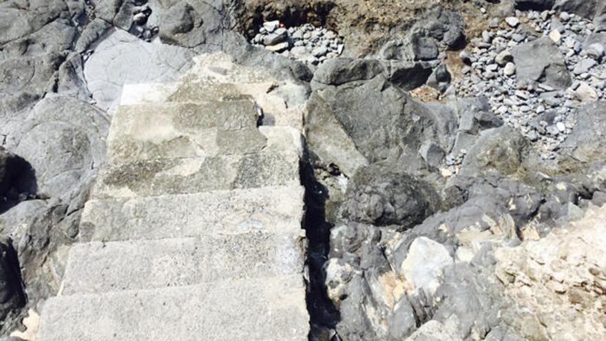 Las olas y las rocas deterioran la escalera de acceso a la playa de Salinetas desde el paseo