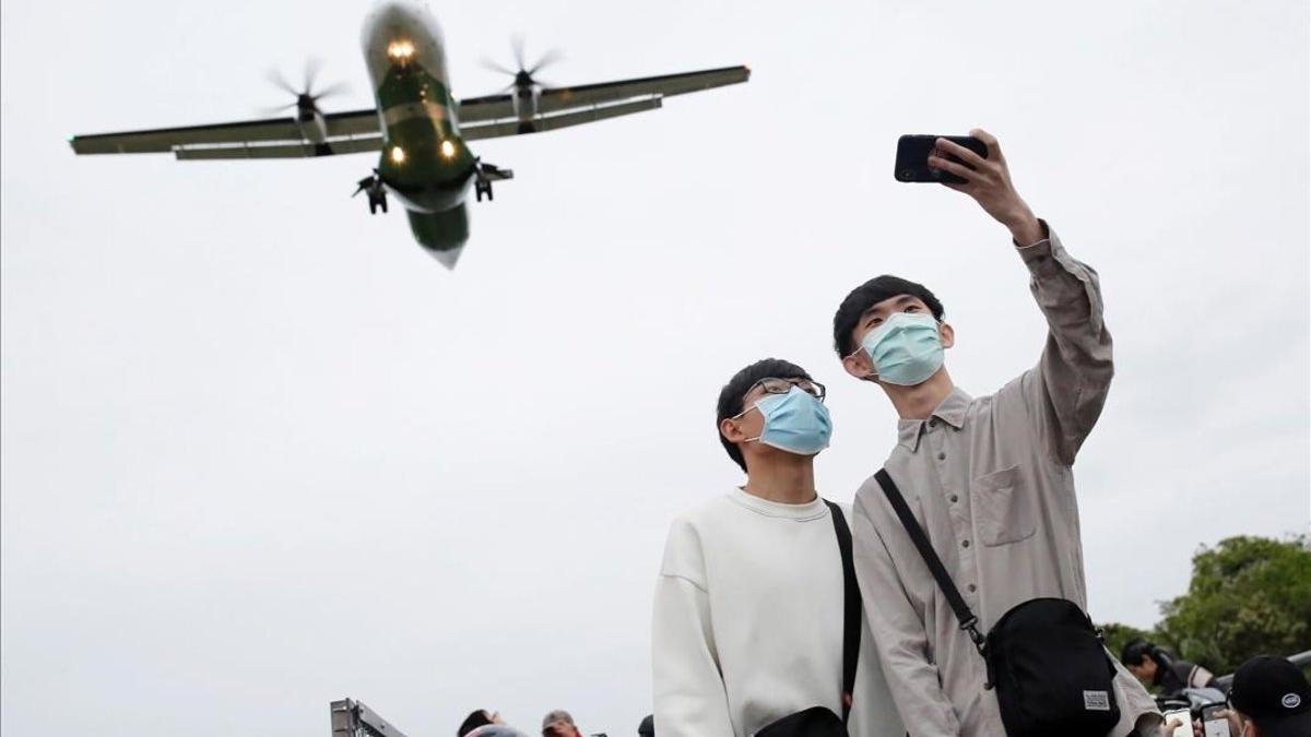Dos jóvenes con mascarillas para protegerse frente al coronavirus se retratan en el aeropuerto de Taipei (Taiwán)