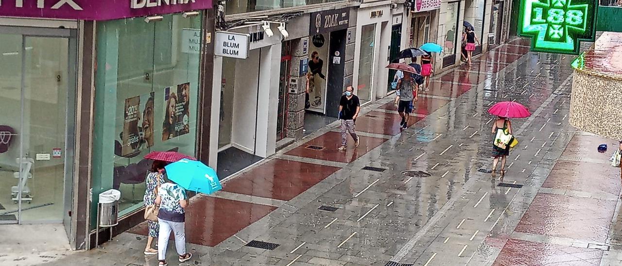 Vecinos en Elche con paraguas en este lunes nuboso y con leves precipitaciones