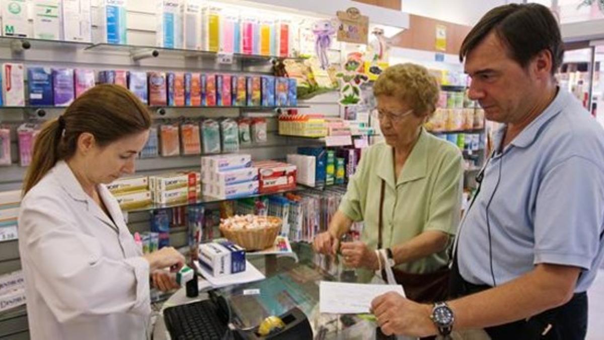 Una dependienta atiende a unos clientes en una farmacia de Barcelona.