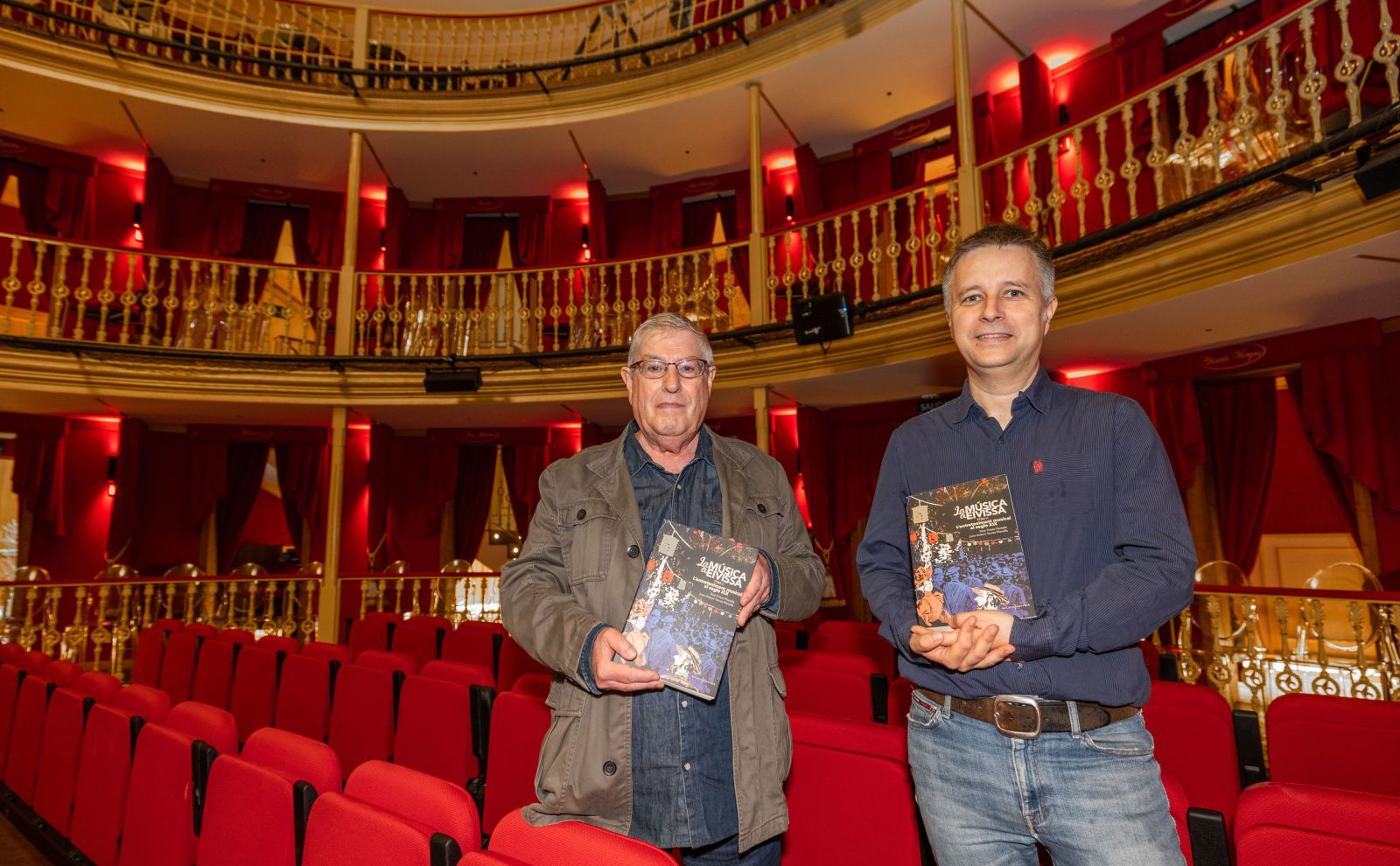 Joan Antoni Torres y Pere Prieto sostienen ejemplares de su libro en el Teatro Pereyra.