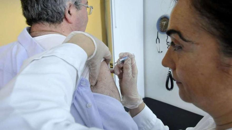 Una enfermera vacuna a una persona contra la gripe. // Fernado Geijo