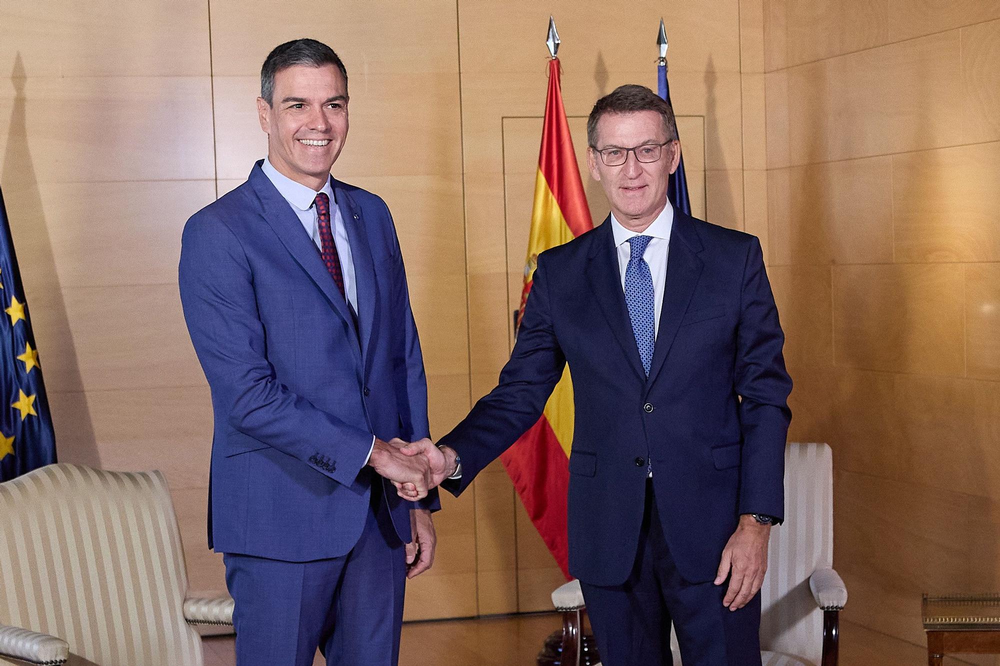 El presidente del Gobierno en funciones y líder del PSOE, Pedro Sánchez (i) y el presidente del PP, Alberto Núñez Feijóo (d), se saludan a su llegada a una reunión en el Congreso.