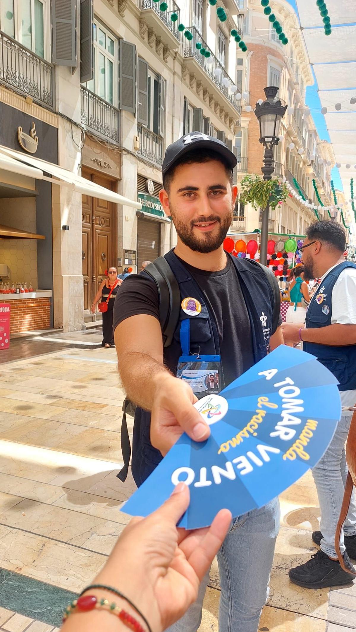 Un voluntario de la asociación reparte un abanico.