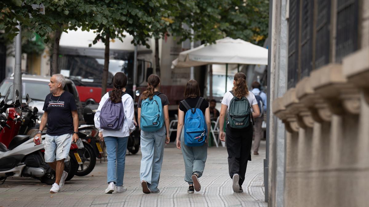 Varias niñas con mochilas sale de un colegio.