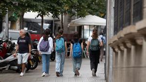 Varias niñas con mochilas sale de un colegio.