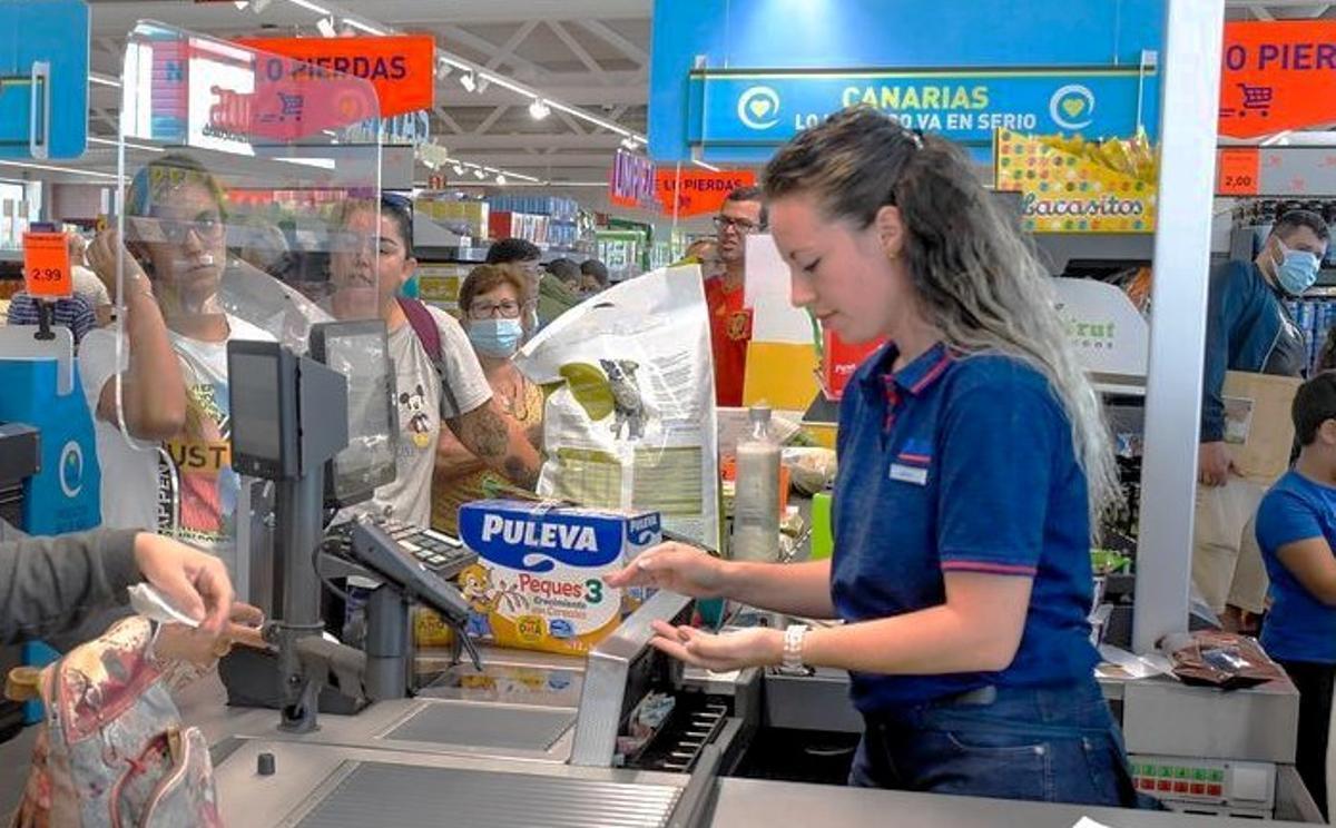 Una cajera de supermercado en su puesto de trabajo cobrando a la clientela.