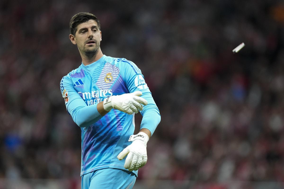Thibaut Courtois, portero del Atlético, lanza uno de los mecheros que le tiraron desde el Fondo Sur del Metropolitano.