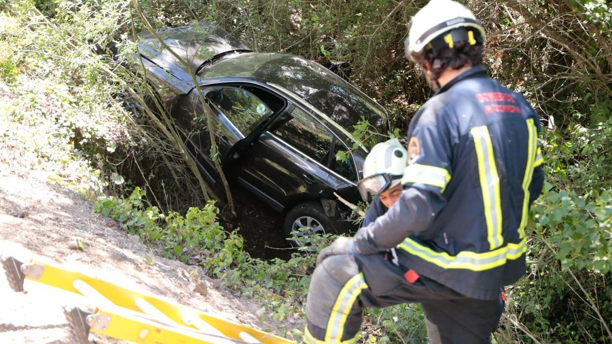 Los bomberos colocan la escalera para rescatar al conductor herido que cayó con su turismo desde hasta la N-122 hasta el arroyo. | Jose Luis Rodríguez