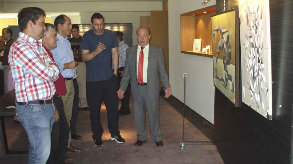 Emilio Benéitez, segundo por la derecha, explica a las autoridades y responsables de Valbusenda el contenido y técnica de su obra. Varias personas admiran un cuadro del artista