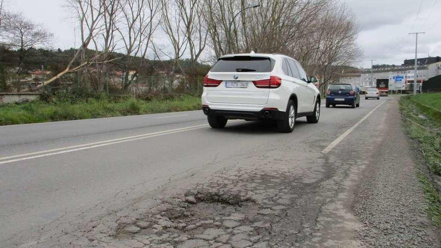 Coches circulan junto a un bache de la avenida de la Diputación, en Arteixo.