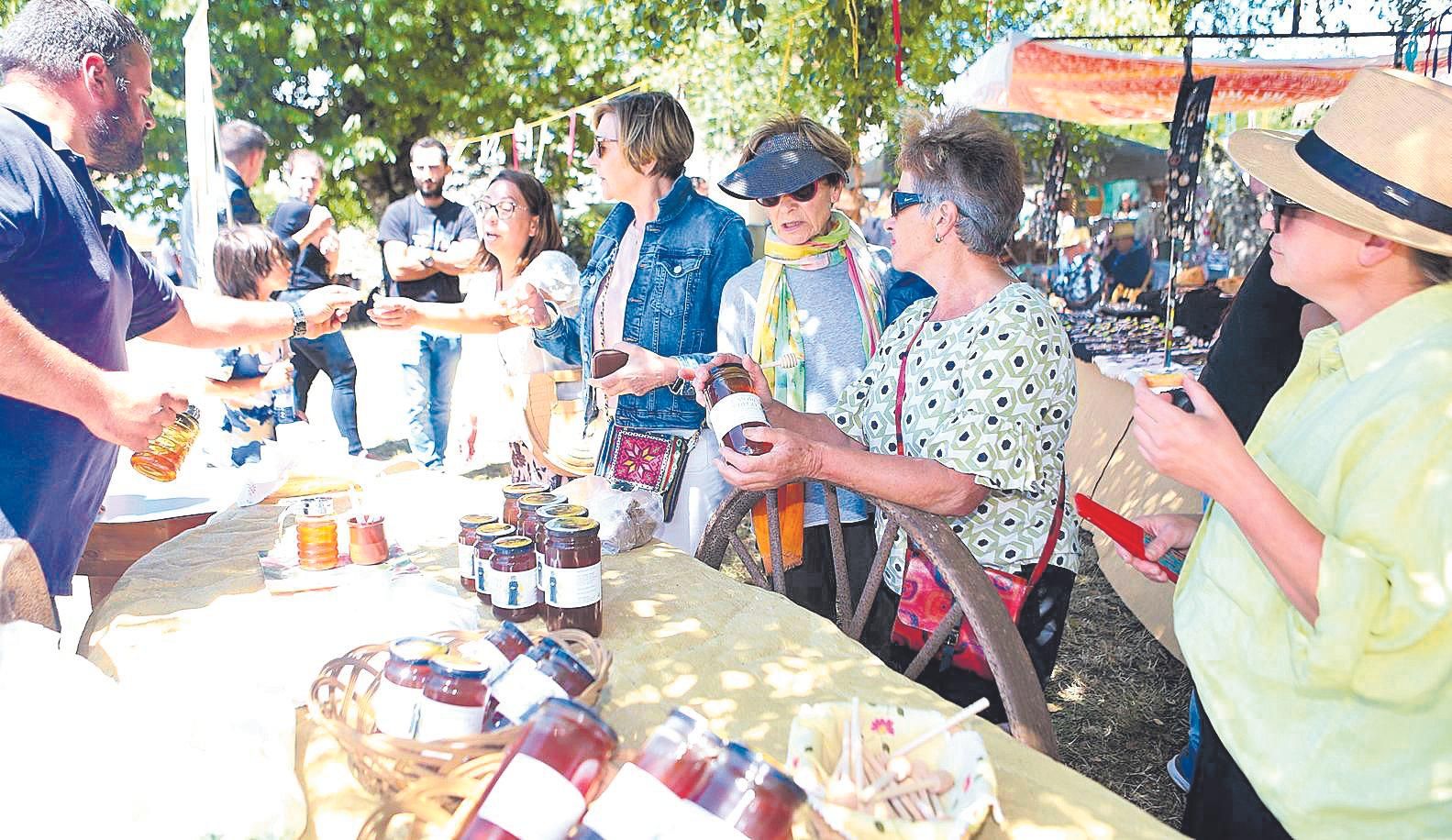 Varias mulleres nun dos postos da feira de artesanía.