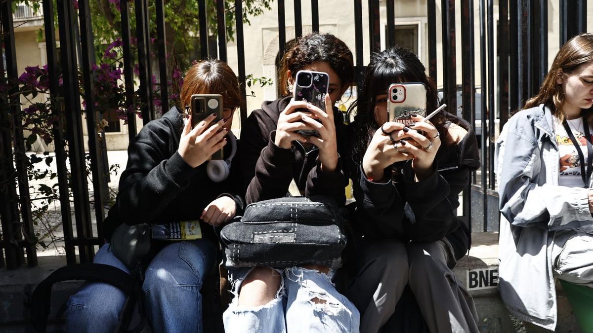 Varias estudiantes del IES Lluis Vives de València con sus teléfonos móviles.