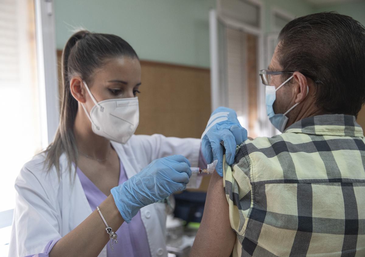 Archivo - Imagen de archivo de una enfermera vacunando a un hombre contra la gripe y la covid-19.