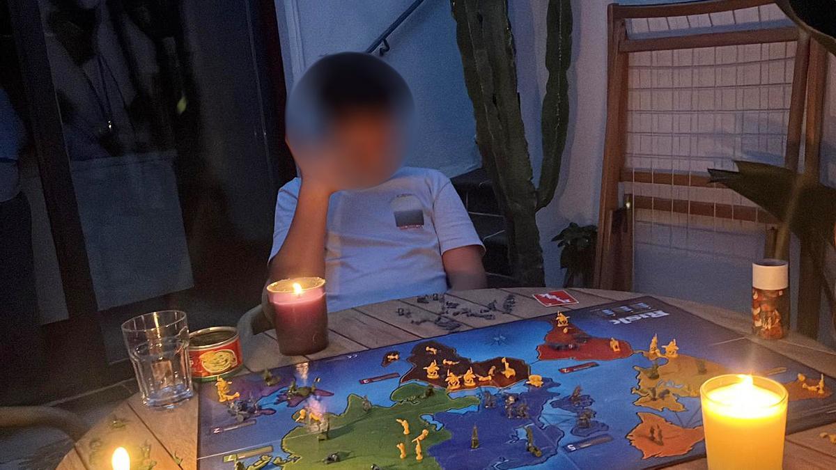 El hijo mediano de Roberto, consultor de Barcelona, jugando al Risk con velas en la terraza de su casa durante el apagón del 28 de abril.