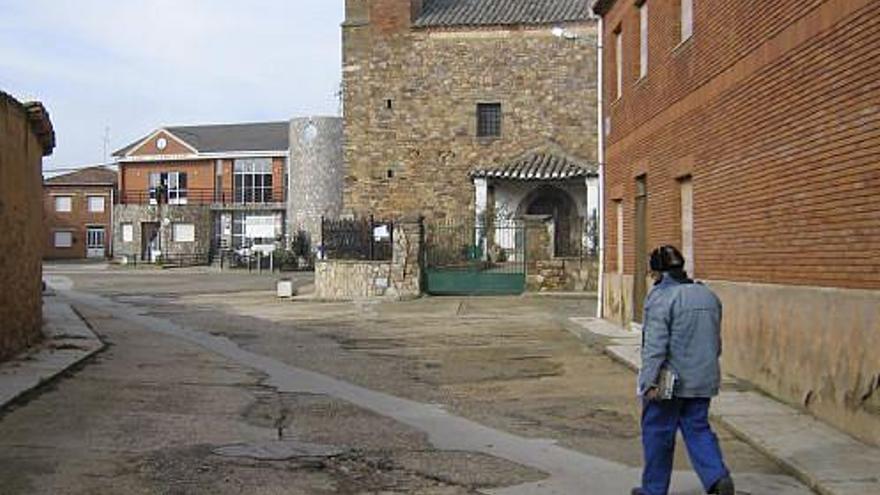 Un vecino de Alcubilla de Nogales en la calle El Rollo. En primer plano, la iglesia y al fondo el nuevo Ayuntamiento.