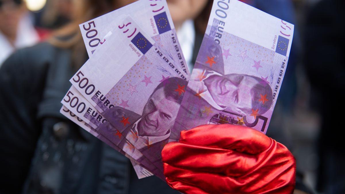 Eine Demonstratin hält Geldscheine mit dem Konterfei von Pedro Sánchez.