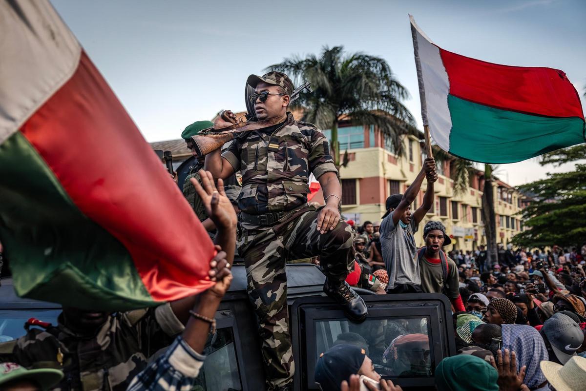 Manifestantes vitorean y agitan banderas frente al Ayuntamiento mientras miembros de la unidad militar CAPSAT viajan en un vehículo blindado. Antananarivo, Madagascar, 11 de octubre de 2025.