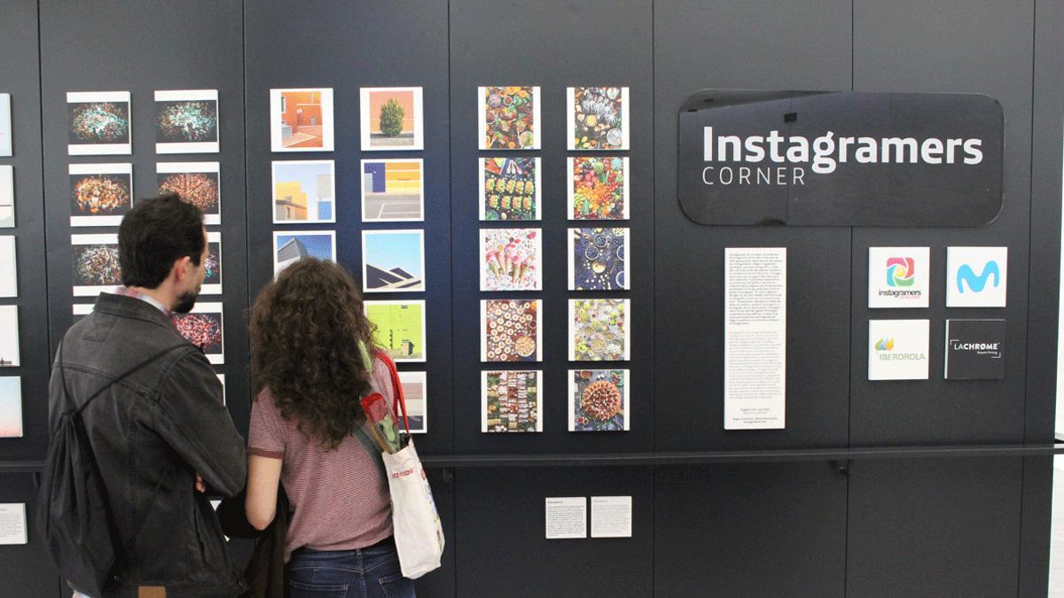 Varias personas contemplan las fotografías expuestas en el Movistar Centre de Barcelona