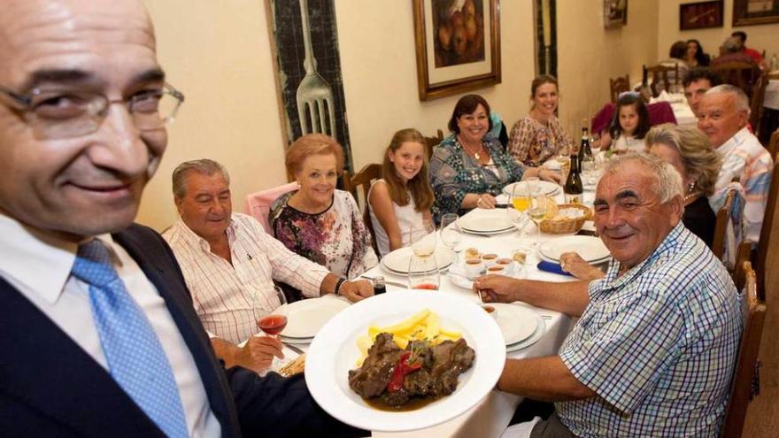 Alfonso Esteban, de Casa Víctor, muestra un plato de rabo de toro a varios comensales.