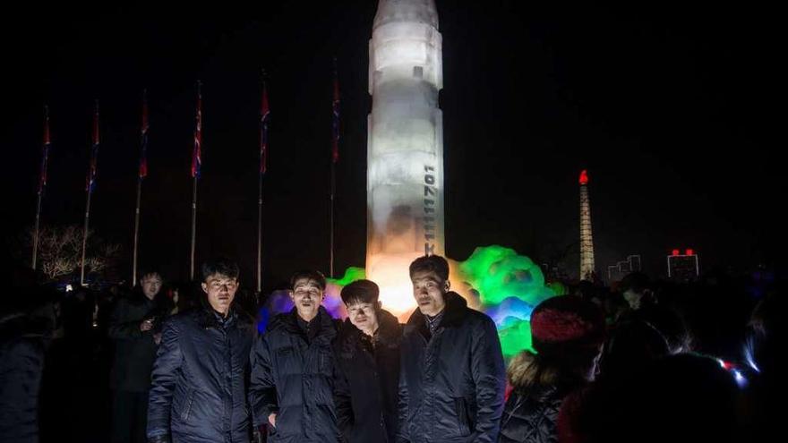 Un grupo de hombres posa ante la réplica en hielo de un misil intercontinental en Pyongyang. // AFP