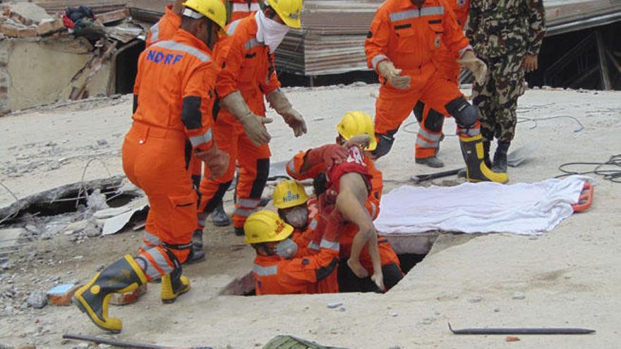 Los bomberos extraen a una niña de los escombros de un edificio.