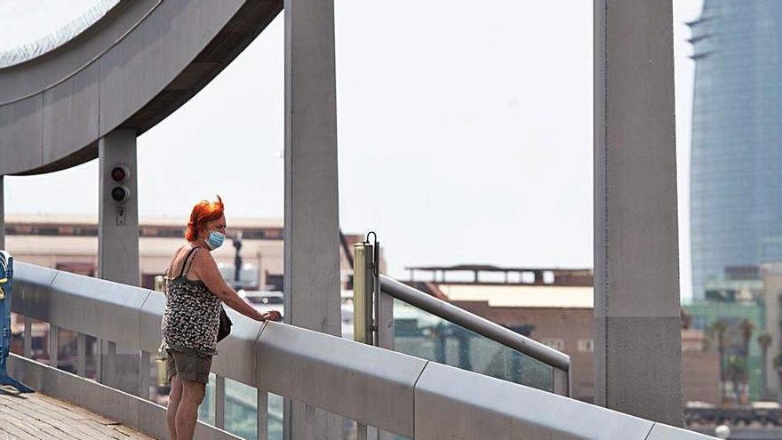 Una dona observa el port de Barcelona amb la mascareta