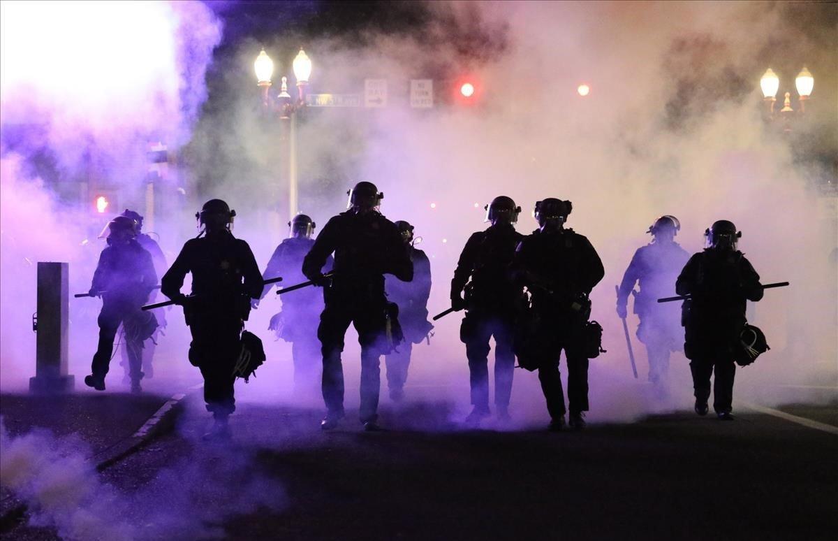  Policías caminan envueltos por gases lacrimógenos en Portland.