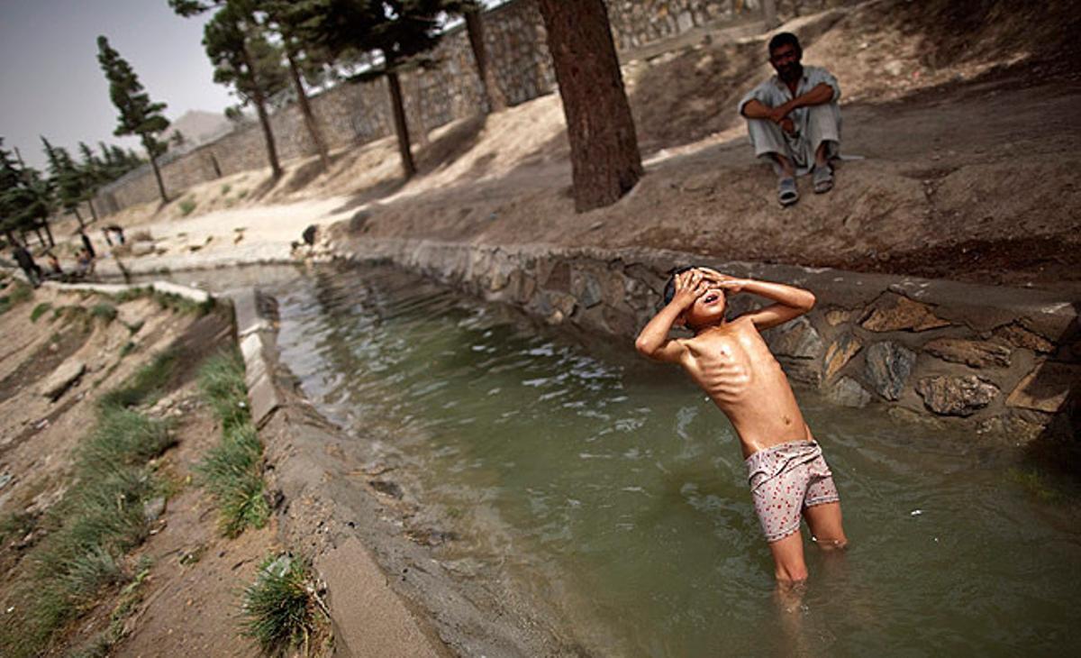 Un nen afganès es banya en un canal a Kabul.