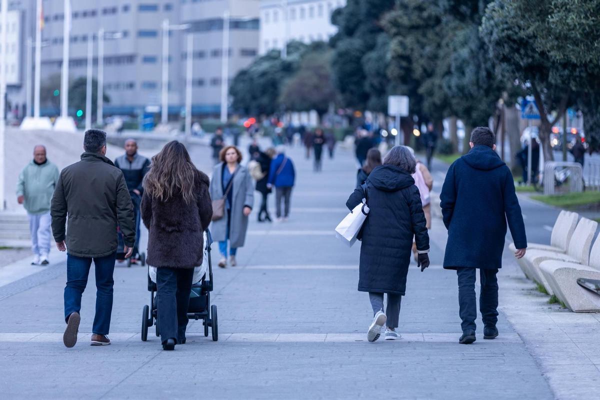 Varias personas caminan por el paseo marítimo de A Coruña un día de invierno.