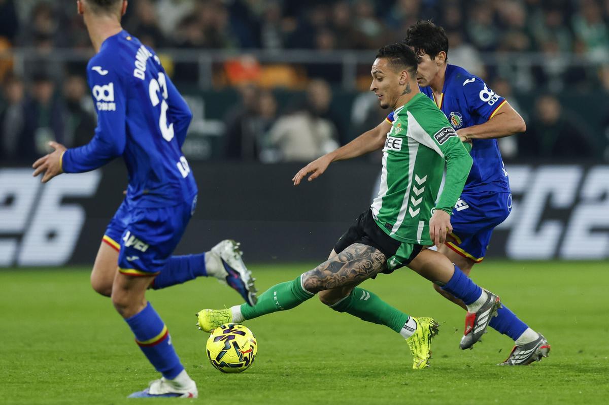 SEVILLA, 21/12/2025.- El delantero brasilero del Betis Antony (c) con el balón ante la defensa del Getafe este domingo, durante el partido de la jornada 17 de LaLiga EA Sports, que Real Betis y Getafe CF disputan en el estadio La Cartuja de Sevilla. EFE/ Julio Muñoz