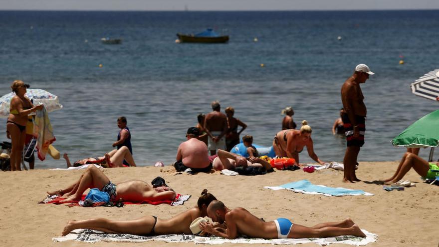 Varios bañistas toman el sol en la playa.