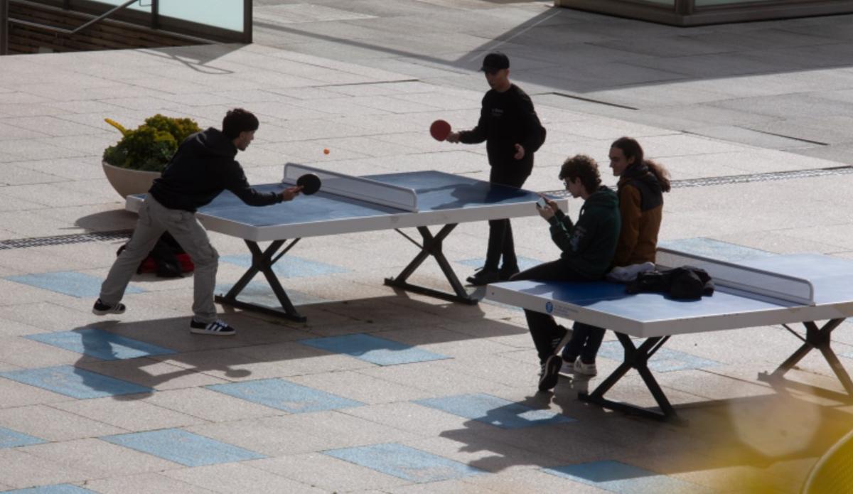 Alumnos universitarios, jungando a tenis de mesa en el campus.