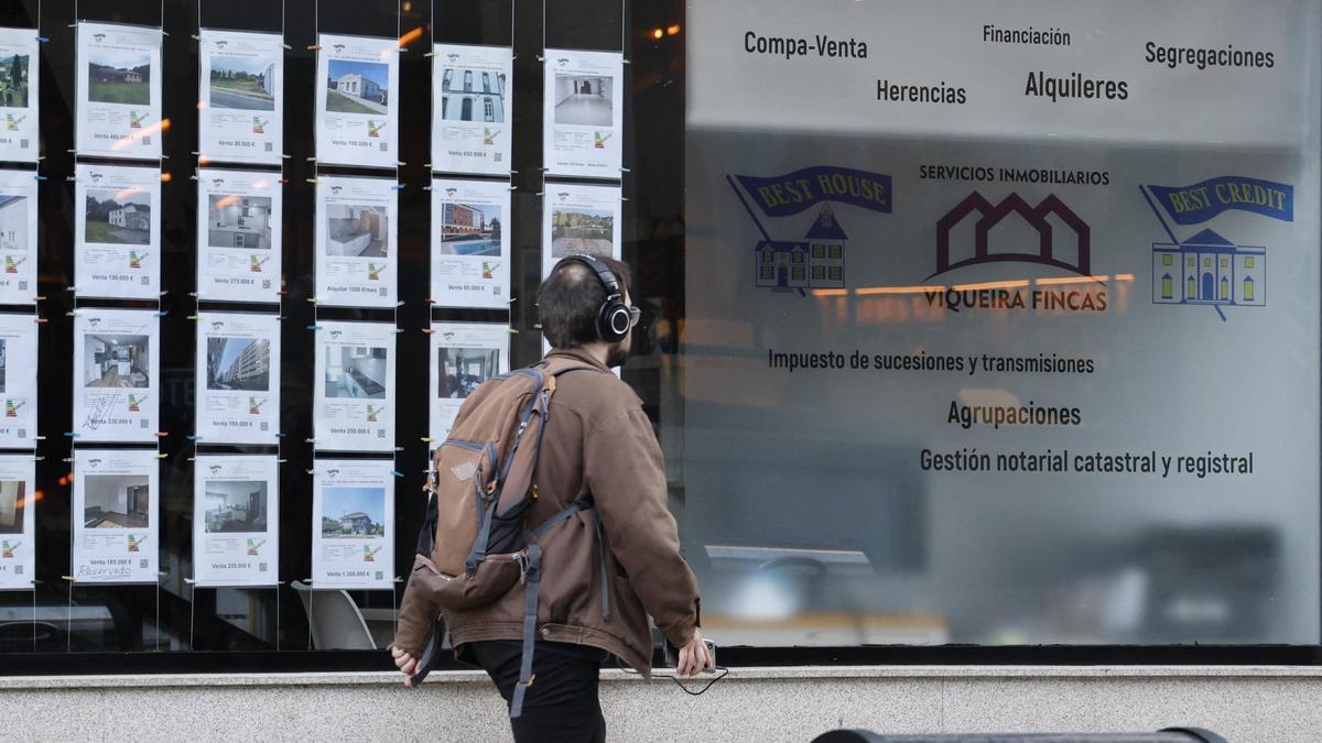 Un joven pasando por delante de una inmobiliaria en Santiago de Compostela