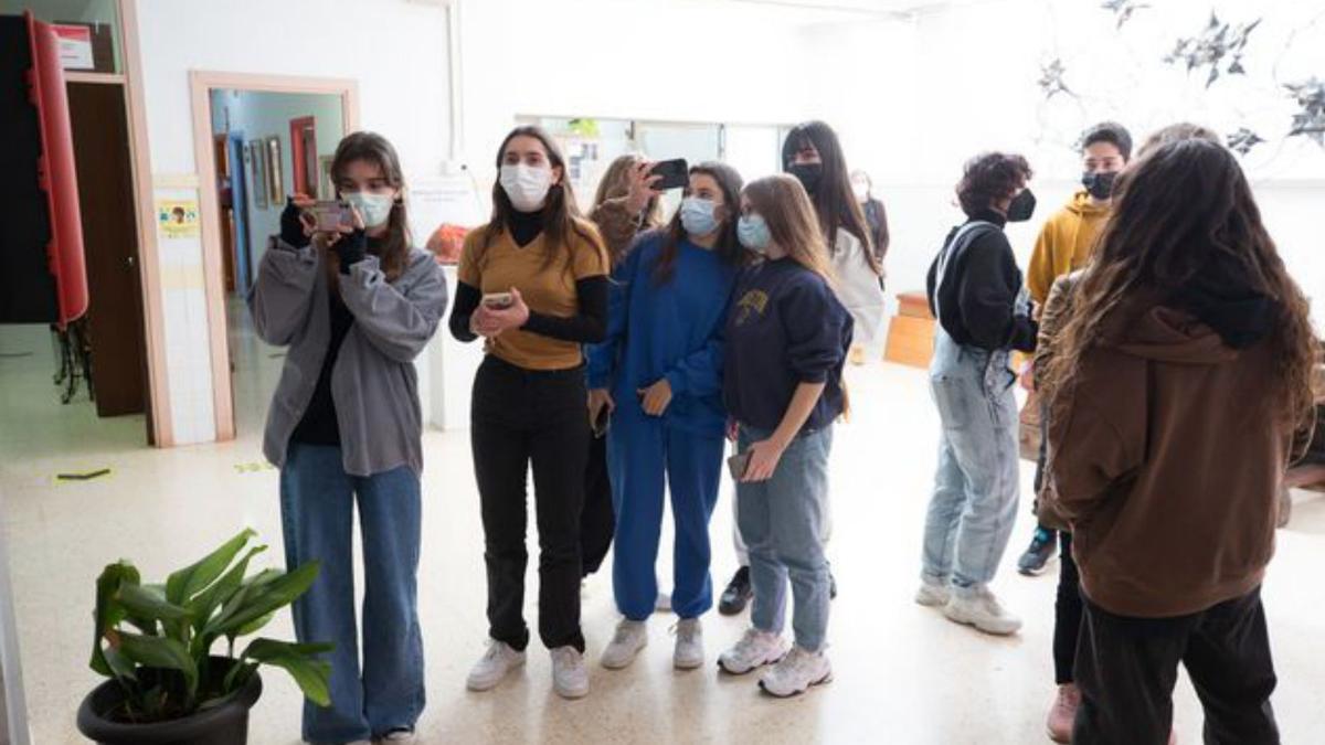 Algunos estudiantes retratan con sus móviles el mural, en la entrada del centro educativo.