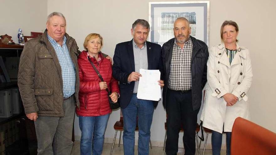 El alcalde, Manuel Cuíña, muestra el documento de compra junto a los dueños de la finca.