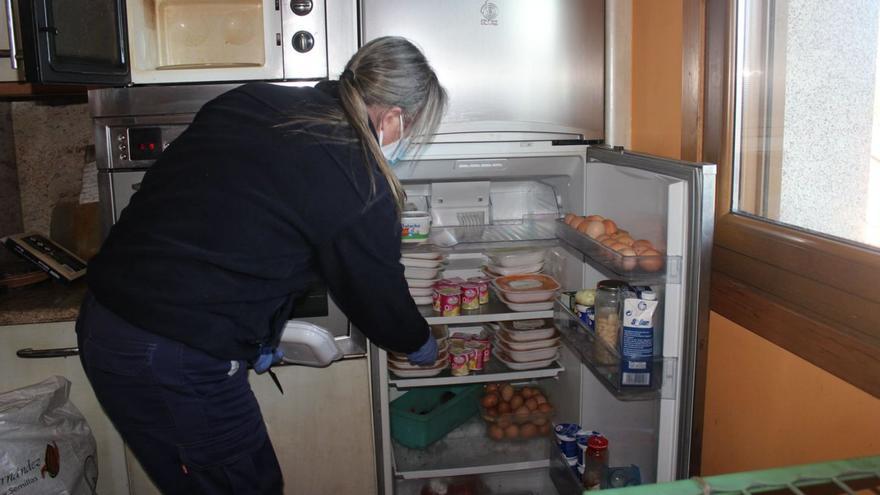 Una mujer deposita en la nevera de un usuario de Xantar na Casa sus menús semanales. |   // FDV