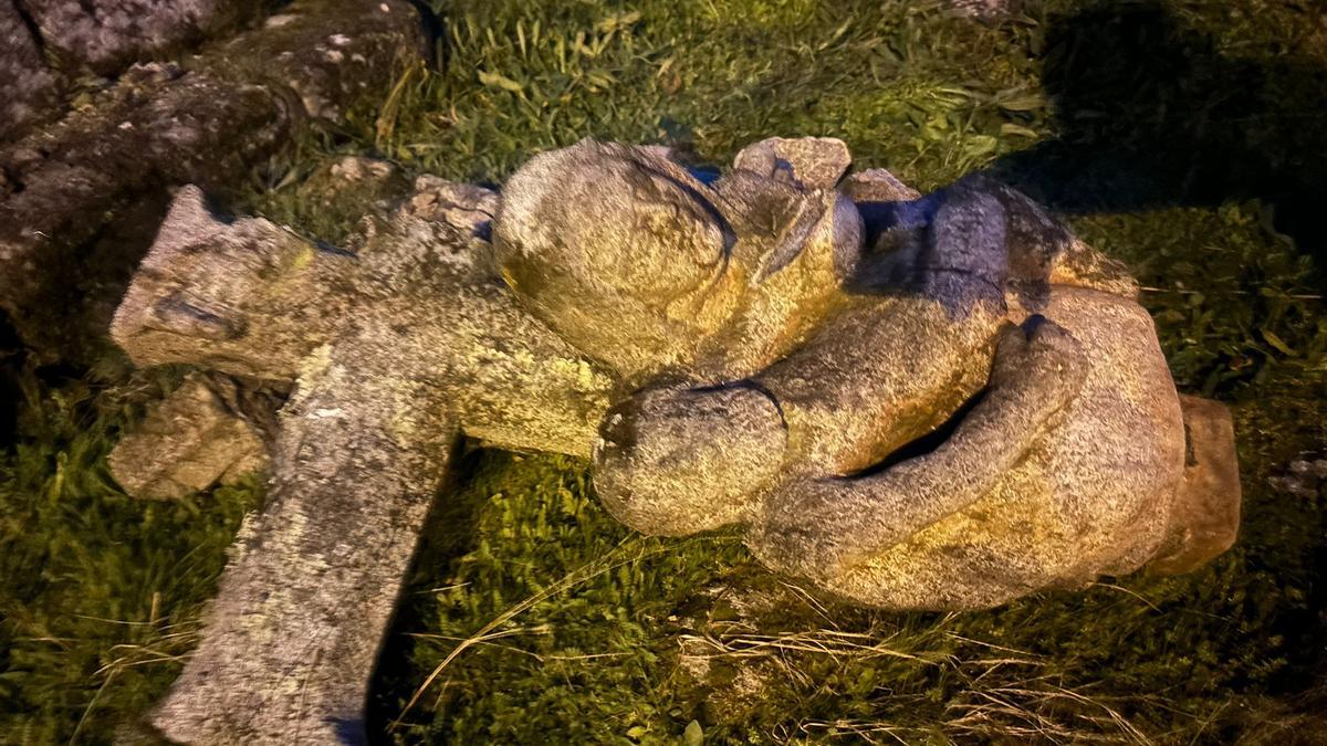 El crucifijo y la Piedad que coronaban el cruceiro, rotos sobre la hierba.